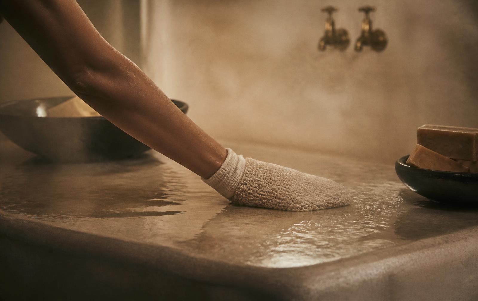 Gommage au gant kessa sur une pierre de hammam